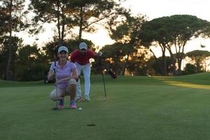 paar Aan golf Cursus Bij zonsondergang foto