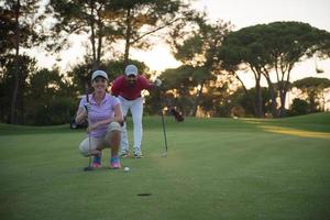 paar Aan golf Cursus Bij zonsondergang foto