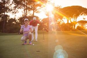 paar Aan golf Cursus Bij zonsondergang foto