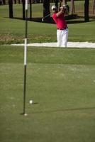 golfspeler raken een zand bunker schot foto