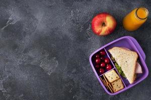heerlijk gezond belegd broodje in een lunch doos, koekjes en kersen. nemen lunch met u naar school- of de kantoor. sap in een fles en een appel. foto