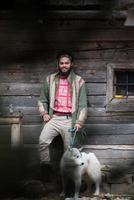 hipster met hond in voorkant van houten huis foto
