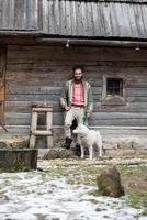 hipster met hond in voorkant van houten huis foto