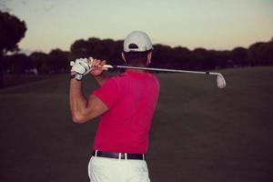 golfspeler raken een zand bunker schot Aan zonsondergang foto