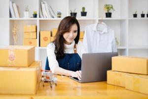 werk van huis. gelukkig Dames verkoop producten online begin een klein bedrijf eigenaar door gebruik makend van laptop computer naar berekenen prijzen en bereiden voor port. foto