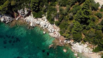 drone-uitzichten vanuit de lucht over een rotsachtige kustlijn, kristalhelder Egeïsch zeewater, toeristische stranden en veel groen op het eiland Skopelos, Griekenland. een typisch beeld van veel vergelijkbare Griekse eilanden. foto