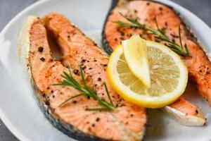 gegrild Zalm steak met kruiden en specerijen rozemarijn Aan bord achtergrond - dichtbij omhoog gekookt Zalm vis filet steak zeevruchten foto