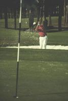 golfspeler raken een zand bunker schot foto