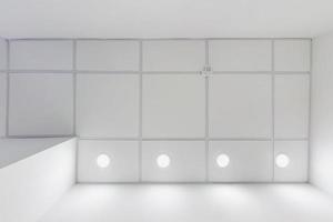 cassette geschorst plafond met plein halogeen vlekken lampen en gipsplaat bouw in leeg kamer in appartement, kliniek, kantoor of huis. rekken plafond wit en complex vorm geven aan. op zoek omhoog visie foto