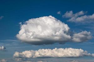 blauwe hemelachtergrond met grote witte kleine stratus cirrus gestreepte wolken foto