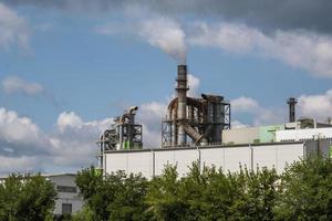 pijpen van houtbewerking onderneming plant zagerij in de buurt van rivier. luchtvervuiling concept. industrieel landschap milieuvervuiling afval van thermische elektriciteitscentrale foto