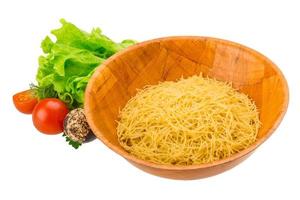 rauwe pasta in een kom op witte achtergrond foto