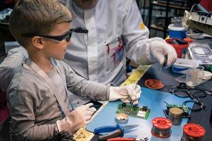 weinig jongen repareren moeder bord met helpen van zijn docent. foto