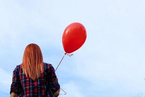 achterzijde visie van vrouw met rood ballon tegen de lucht. foto