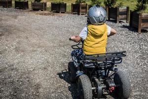 weinig jongen genieten van in van de weg af rijden Aan atv voertuig. foto