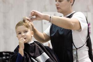 klein jongen krijgen een kapsel Bij de salon. foto