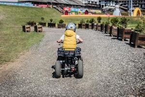 achterzijde visie van kind aan het leren naar rit atv van de weg af voertuig. foto