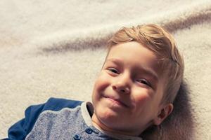 schattig gelukkig kind ontspannende Aan de bed. foto