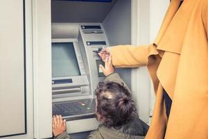 weinig meisje intrekken geld het formulier Geldautomaat met helpen van moeder. foto