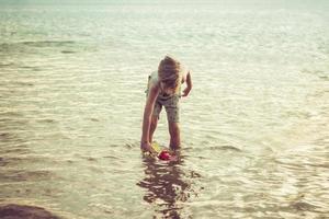 klein jongen spelen in water gedurende zomer dag. foto