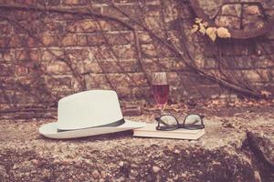 fedora hoed met boek en glas van wijn. foto