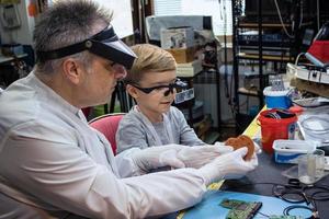 wetenschap leraar en klein jongen onderzoeken computer een deel. foto