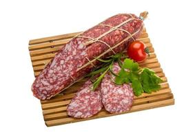 salami Aan houten bord en wit achtergrond foto