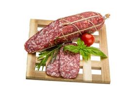 salami Aan houten bord en wit achtergrond foto