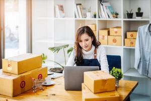 werk van huis. gelukkig Dames verkoop producten online begin een klein bedrijf eigenaar door gebruik makend van laptop computer naar berekenen prijzen en bereiden voor port. foto