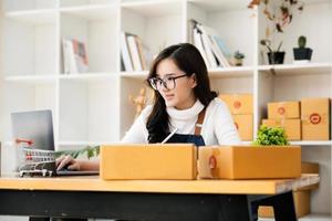 werk van huis. gelukkig Dames verkoop producten online begin een klein bedrijf eigenaar door gebruik makend van laptop computer naar berekenen prijzen en bereiden voor port. foto