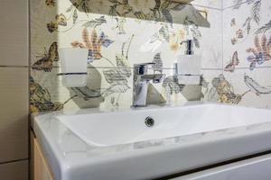 keramische waterkraan gootsteen met kraan met zeep en shampoo dispensers in dure loft badkamer of keuken foto