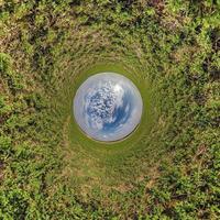 blauwe bol kleine planeet binnen groen gras ronde frame achtergrond. foto