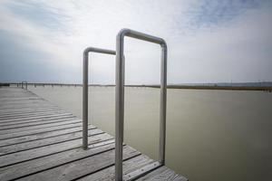 een houten steiger met aluminium pooldeck ladder met leuning op neusiedlersee in oostenrijk. foto