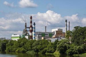 pijpen van houtbewerking onderneming plant zagerij in de buurt van rivier. luchtvervuiling concept. industrieel landschap milieuvervuiling afval van thermische elektriciteitscentrale foto