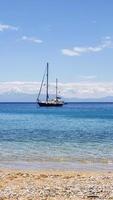 kleine toeristische schip zeilen in de buurt van het strand op blauwe golven van rechts naar links. foto