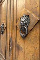 oud houten deuren met ringen en oubollig wijnoogst staal klopper omgaan met vormig Leuk vinden een leeuw hoofd dichtbij omhoog in Italië. foto