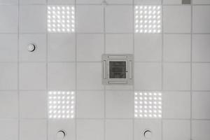 cassette verlaagd plafond met vierkante halogeenspots lampen en gipsplaten constructie in lege ruimte in appartement of huis. spanplafond wit en complexe vorm. omhoog kijken foto