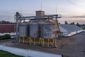 modern graanschuur lift met zilver silo's Aan agro-verwerking en fabricage fabriek voor verwerken drogen schoonmaak en opslagruimte van agrarisch producten, meel, granen en korrel. foto