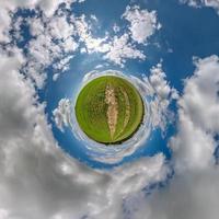 groene kleine planeet in blauwe lucht met prachtige wolken. transformatie van bolvormig panorama 360 graden. sferische abstracte luchtfoto. kromming van de ruimte. foto