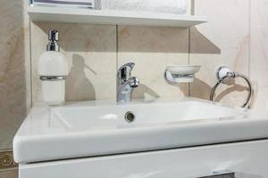 keramische waterkraan gootsteen met kraan met zeep en shampoo dispensers in dure loft badkamer of keuken foto