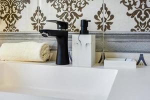 keramische waterkraan gootsteen met kraan met zeep en shampoo dispensers in dure loft badkamer of keuken foto