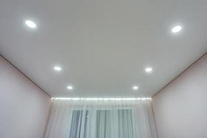 verlaagd plafond met halogeenspots lampen en gipsplaten constructie in lege ruimte in appartement of huis. spanplafond wit en complexe vorm. foto