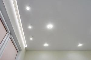 verlaagd plafond met halogeenspots lampen en gipsplaten constructie in lege ruimte in appartement of huis. spanplafond wit en complexe vorm. foto