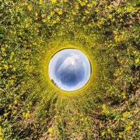 inversie van kleine planeet transformatie van bolvormig panorama 360 graden. sferische abstracte luchtfoto in koolzaadveld met geweldige mooie wolken. kromming van de ruimte. foto
