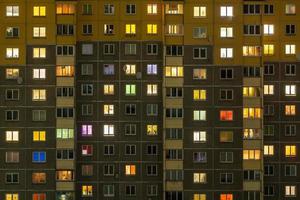 plat nachtpanorama van veelkleurig licht in ramen van gebouwen met meerdere verdiepingen. leven in de grote stad foto