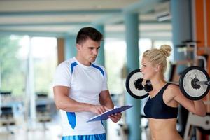 jong sportief vrouw met trainer oefening gewichten hijs- foto