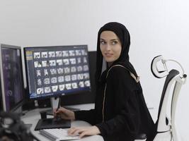 moslim vrouw grafisch ontwerper werken Aan computer gebruik makend van grafisch tablet en twee monitoren foto
