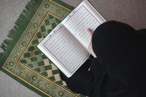 midden- oostelijk vrouw bidden en lezing de heilig koran foto