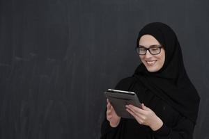 jong Arabisch zakenvrouw in traditioneel kleren of abaya Holding tablet computer foto