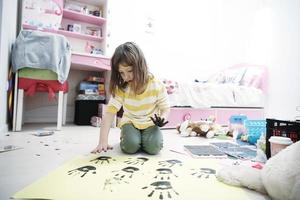 schattig weinig meisje Bij huis schilderij met handen foto